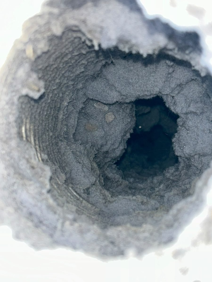 Dryer vent duct packed with gray lint before cleaning