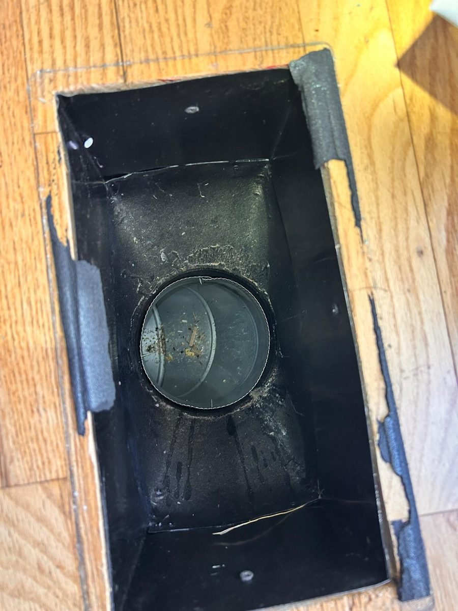 Floor register opening with debris collected in the duct